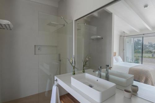a white bathroom with a sink and a bed at Amaria in Aljezur