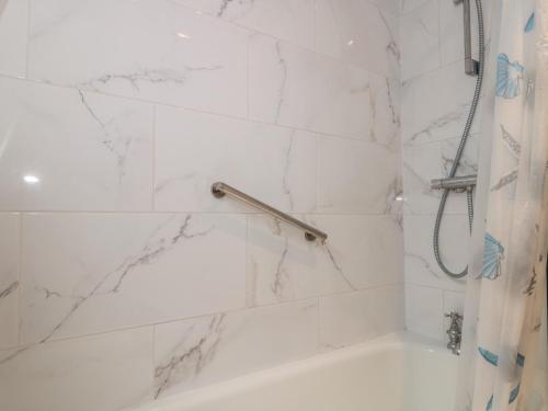 een witte badkamer met een douche en een bad bij Bay View in Swanage