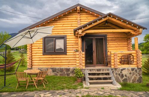 a wooden cabin with a table and an umbrella at Eco House Borjomi in Borjomi