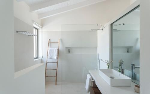 a white bathroom with a sink and a mirror at Amaria in Aljezur