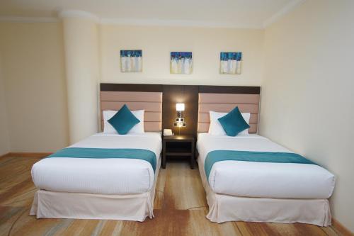 two beds in a hotel room with blue pillows at Best Western Premier Dynasty in Addis Ababa