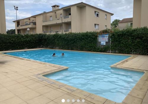 2 persone che nuotano in una piscina accanto a un edificio di Charmant appartement - Residence avec piscine a Montpellier
