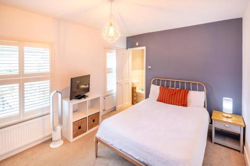 a bedroom with a white bed and a tv at The Railway Inn MK - Victorian 3-Bedroom Home with Sauna, Jacuzzi Bath, FAST WI-FI & Free Parking in Milton Keynes
