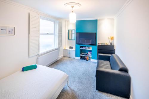 a living room with a couch and a tv at The Railway Inn MK - Victorian 3-Bedroom Home with Sauna, Jacuzzi Bath, FAST WI-FI & Free Parking in Milton Keynes