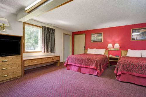 a hotel room with two beds and a flat screen tv at Travelodge by Wyndham Red Wing in Red Wing