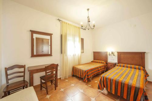 1 dormitorio con 2 camas, mesa y sillas en Alojamientos Rurales Berrocal, en Berrocal