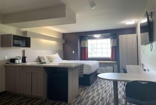 a hotel room with a bed and a kitchen with a sink at Microtel Inn & Suites by Wyndham Bossier City in Bossier City