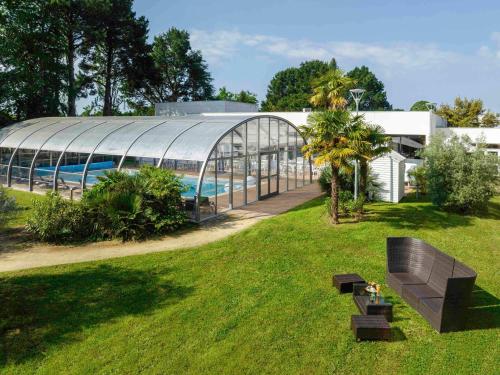 un bâtiment avec une piscine et un banc en gazon dans l'établissement Novotel Nantes Carquefou, à Carquefou