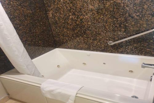 a white bath tub in a bathroom with a wall at Super 8 by Wyndham Cypress Buena Park Area in Cypress
