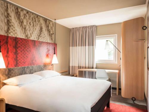 um quarto de hotel com uma cama grande e uma secretária em ibis London Heathrow Airport em Hillingdon