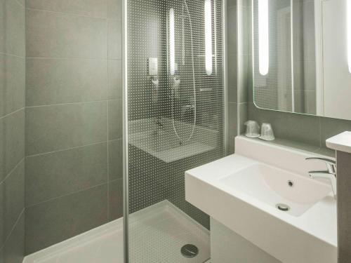 a bathroom with a shower and a sink and a mirror at ibis London Heathrow Airport in Hillingdon