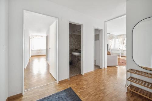 um amplo quarto branco com um espelho e piso em madeira em Beautiful Boutique Apartment DRAHTZUG16 em Zürich