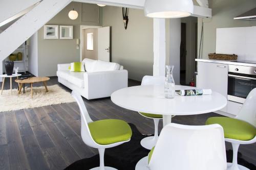 sala de estar con mesa blanca y sillas verdes en Entre Deux Pays Apartments en Spa