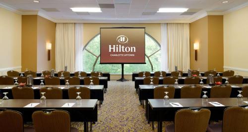 a conference room with tables and chairs and a screen at Hilton Charlotte Uptown in Charlotte