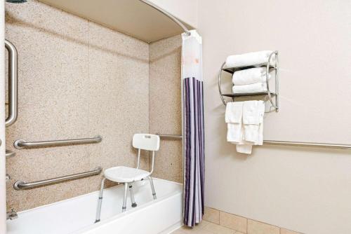 a bathroom with a tub and a chair next to a shower at La Quinta by Wyndham Ada in Ada