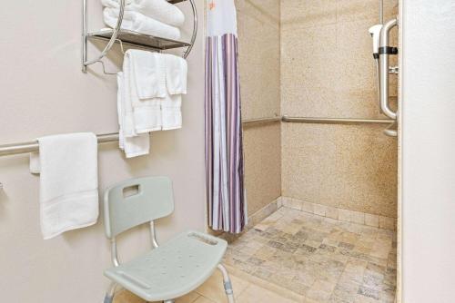a bathroom with a shower and a chair in it at La Quinta by Wyndham Ada in Ada