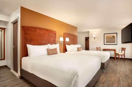 a hotel room with two beds and a table at Days Inn & Suites by Wyndham Sherwood Park Edmonton in Sherwood Park