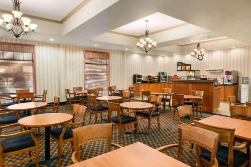 a restaurant with tables and chairs and a kitchen at Days Inn & Suites by Wyndham Edmonton Airport in Leduc