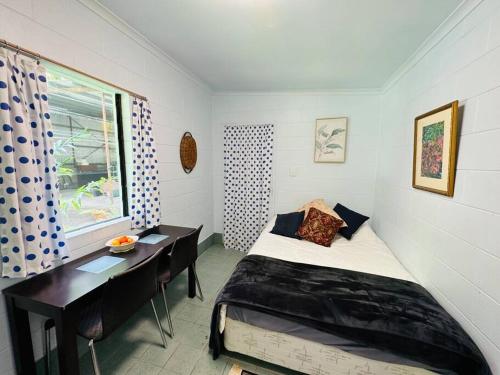 a bedroom with a bed and a desk and a window at Bamboo Cabin in Kuranda