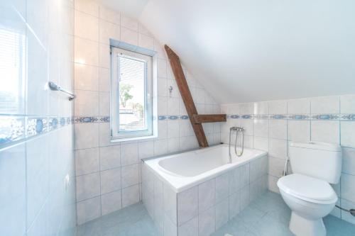 ein Bad mit einer Badewanne, einem WC und einem Fenster in der Unterkunft Pod Lipami in Rewal
