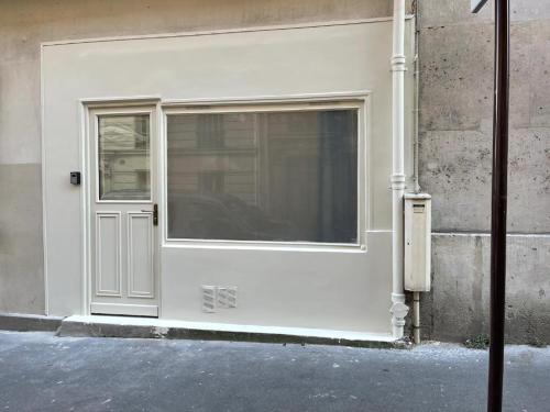 une porte blanche avec une fenêtre sur le côté du bâtiment dans l'établissement Mathurin, à Paris