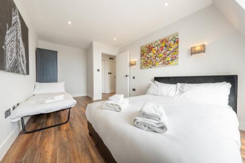 a bedroom with a large white bed and a chair at 8 - West London Brand New Loft in London