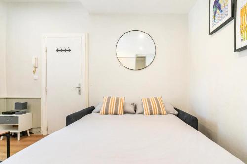 Schlafzimmer mit einem weißen Bett und einem Spiegel in der Unterkunft L'Aquarelle - Studio cosy proche du métro in Toulouse
