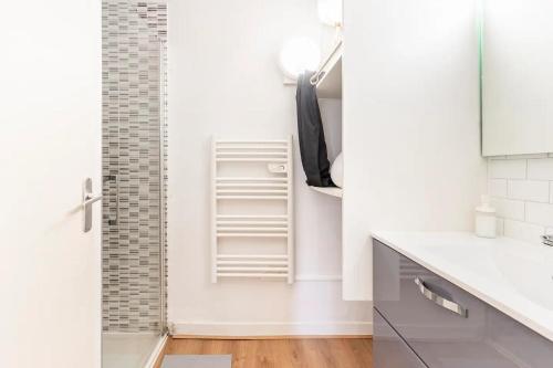 ein weißes Bad mit einer Dusche und einem Waschbecken in der Unterkunft L'Aquarelle - Studio cosy proche du métro in Toulouse
