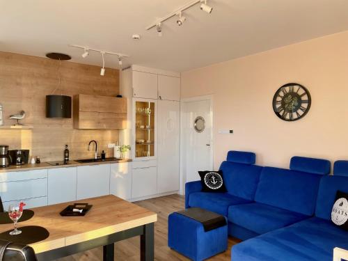 een woonkamer met een blauwe bank en een tafel bij Perlowa Przystan - Apartamenty KOMFORT widok na morze, parking in Sianozety