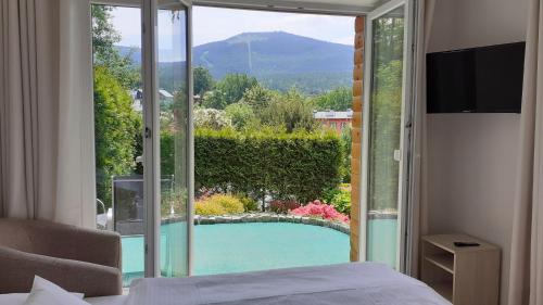 シュクラルスカ・ポレンバにあるWilla Ambraのベッドルーム1室(スイミングプールの景色を望むガラスドア付)