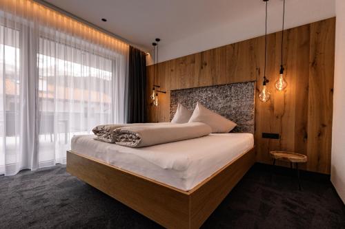 a bedroom with a bed with a wooden wall at DAS MORITZ- Fine Living Apartments in Nauders