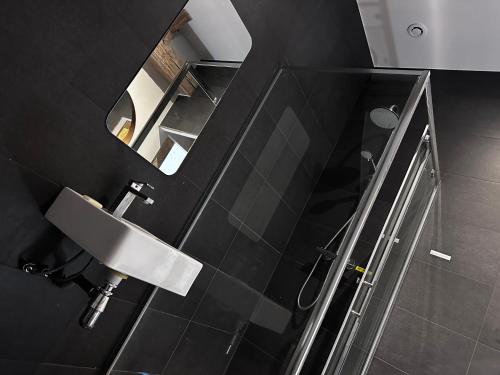 ein schwarzes Bad mit einem Waschbecken und einem Spiegel in der Unterkunft Maison au bord de l’eau in Annay-sur-Serein