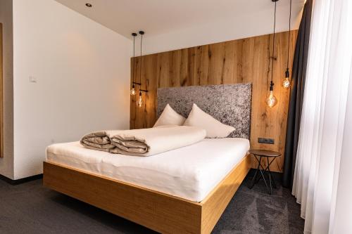 a bedroom with a bed with a wooden headboard at DAS MORITZ- Fine Living Apartments in Nauders