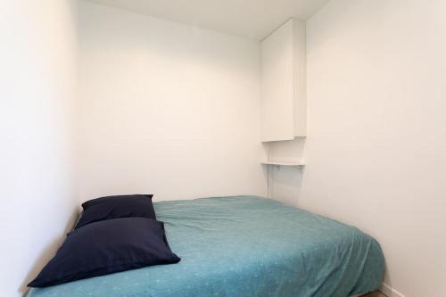 Ce lit se trouve dans une chambre blanche dotée d'une couverture bleue. dans l'établissement Très beau T3 proche RER Port Royal 6 pers, à Paris