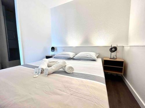 een slaapkamer met een bed met witte lakens en kussens bij T1bis avec terrasse et parking privés LE MIAMI in Perpignan