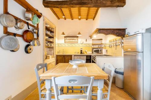 una cucina con tavolo, sedie e frigorifero di La Casa di Vignoni Alto a Bagno Vignoni