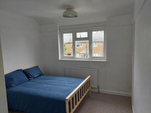 Un dormitorio con una cama azul y una ventana en Lovely 3 bed terraced family house en Kew Gardens