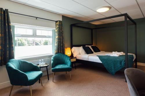 a bedroom with a bed and two chairs at The Imperial Dragon Hotel in Saundersfoot