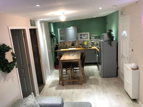 eine Küche mit grünen Wänden, einem Tisch und einem Kühlschrank in der Unterkunft Maisonnette à la campagne rivière SPA et détente in Saint-Seriès