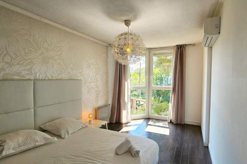 - une chambre avec un lit, un lustre et une fenêtre dans l'établissement Ovalie ! Spacieux T3 lumineux, à Montpellier