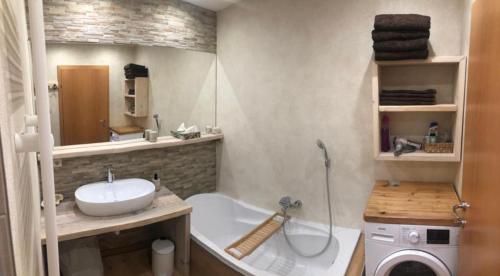 een badkamer met een bad, een wastafel en een wasmachine bij Ennstal Classic Landhaus Chalet in Irdning