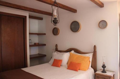 - une chambre avec un lit et des oreillers orange dans l'établissement Retiro Da Avo Lídia - Turismo Rural, à Mendiga