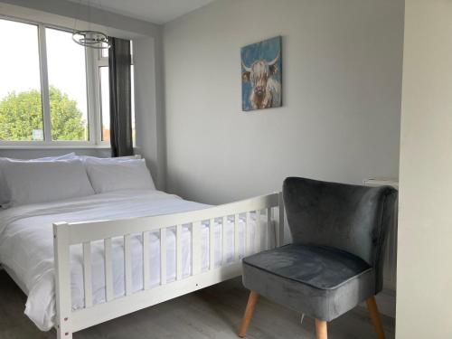 - une chambre avec un lit blanc et une chaise dans l'établissement Highfield Home with free parkings, Surbiton, Kingston upon Thames, Surrey, Greater London , UK, à Surbiton
