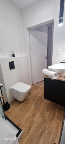 a white bathroom with a toilet and a sink at Apartament Moje Dąbrówno in Dąbrówno
