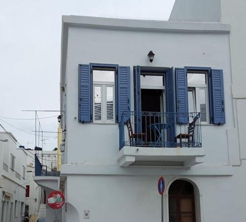 a white building with blue shutters and a balcony at Gyzi 's house in Tinos Town