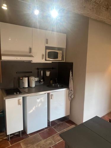 une cuisine avec des armoires blanches et un micro-ondes dans l'établissement Les Litanies - Centre historique Pezenas, à Pézenas