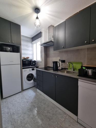 トレビエハにあるTorreSol Apartmentのキッチン(黒いキャビネット、洗濯機、乾燥機付)