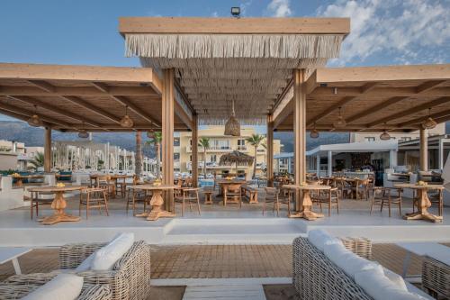 a patio with tables and chairs under a wooden pavilion at Parthenis Beach, Suites by the Sea in Malia