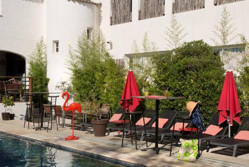 a pool with tables and chairs next to a building at Vila De La Mar & Spa in Saintes-Maries-de-la-Mer