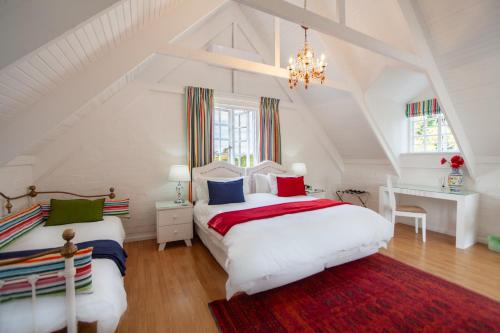 2 camas en un dormitorio blanco en el ático con lámpara de araña en Cosimi Guest House, en Durbanville